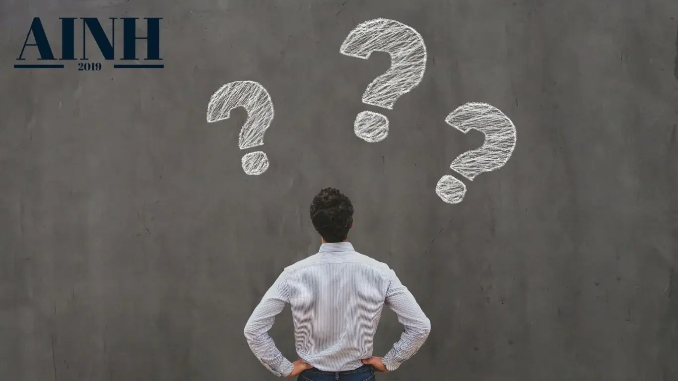 Homme de dos face a un mur gris et point d'interrogations