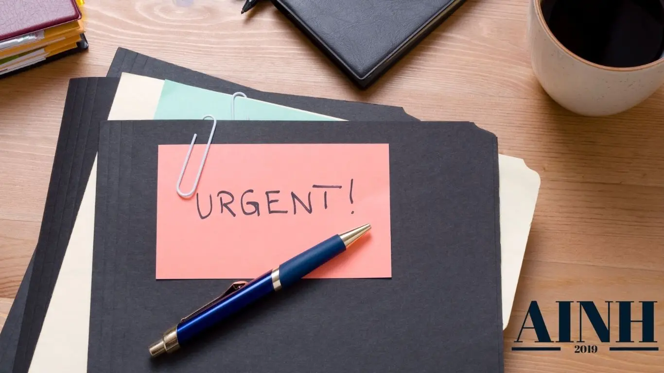 Dossier sur table avec un post-it écrit urgent et une tasse de café sur le coté