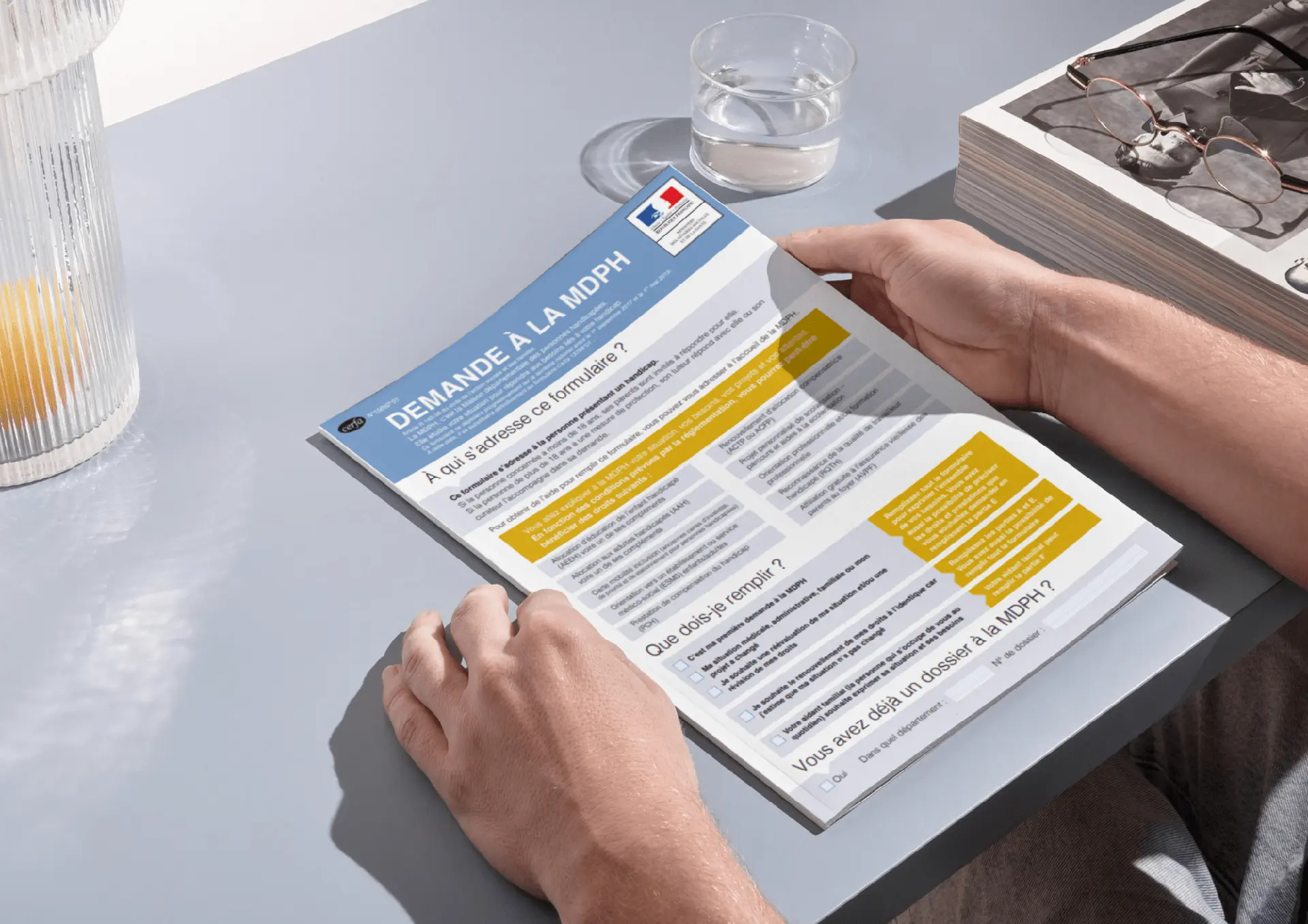 Dossier MDPH tenue dans les mains sur une table avec carafe et verre d eau 